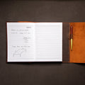 Open notebook with lined pages and a leather cover on a dark surface