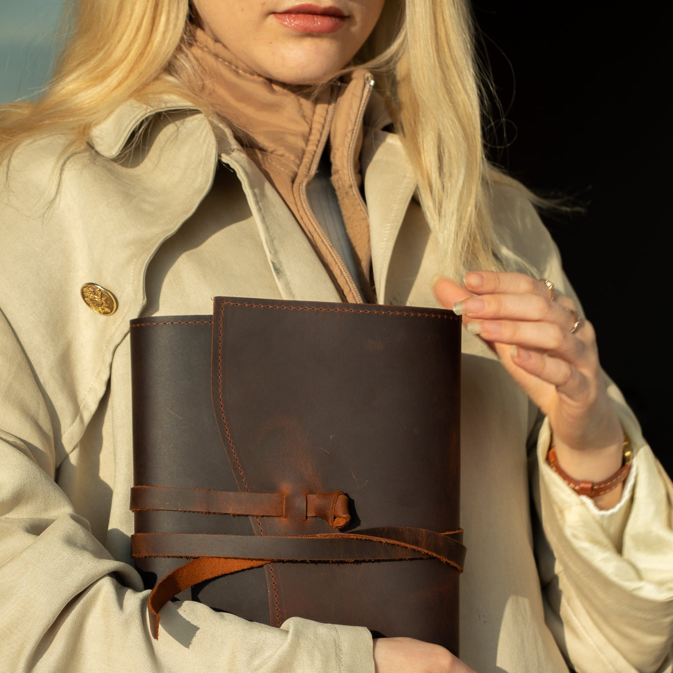 Person holding a brown leather-bound book against a dark background